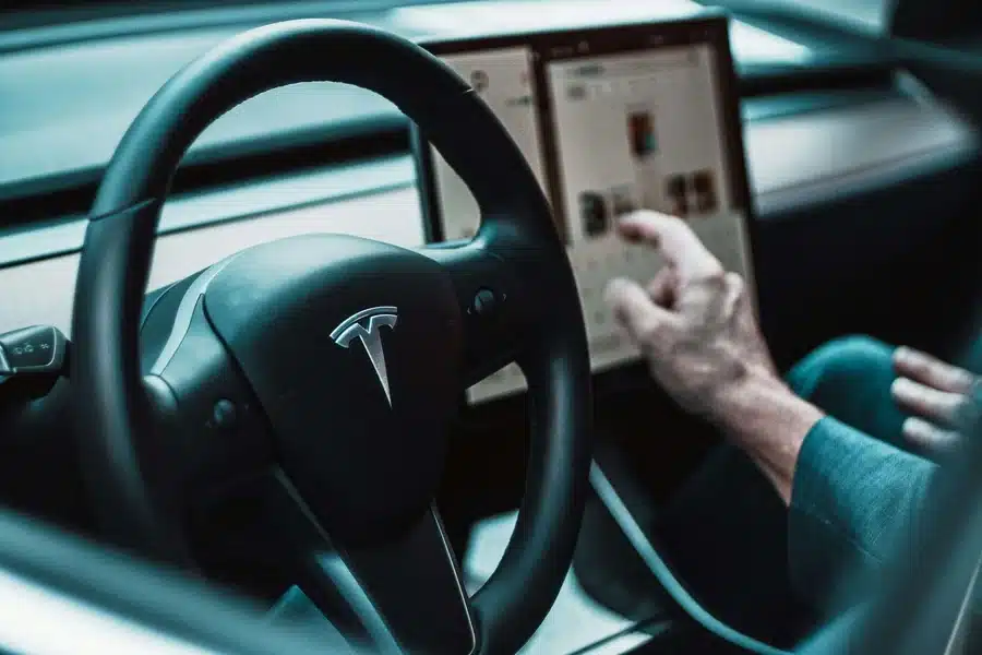 Tesla driver interacting with vehicle touchscreen highlighting software-related issues under California Lemon Law